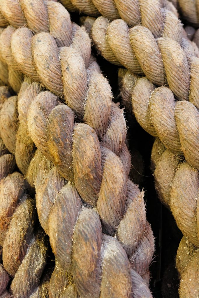 Close-up of intertwined natural fiber ropes in muted tones, showcasing texture and craftsmanship - Intertwined natural fiber ropes exhibit intricate textures and muted colors, highlighting the craftsmanship in their construction.